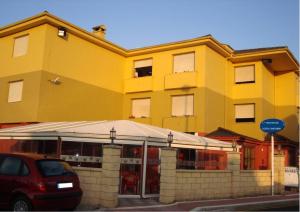 un edificio amarillo con un coche aparcado delante de él en Hotel Costa Cántabra, en Argoños