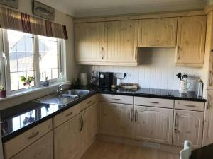 a kitchen with wooden cabinets and black counter tops at The Nest in Modbury