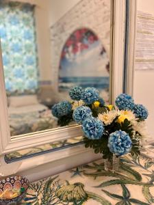 een vaas gevuld met blauwe en witte bloemen naast een spiegel bij B&B 091 in Palermo