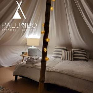 Palumbo Glamping & Villas في كايامبيه: غرفة نوم بها مظلة مع سرير وطاولة