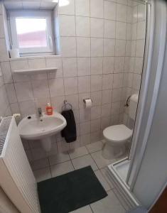 a white bathroom with a sink and a toilet at Bellis - Apartmanok in Szilvásvárad