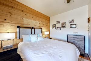 Un dormitorio con una cama blanca y una pared de madera. en Riverfront Lodge, en Pagosa Springs