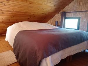 a bed in a room with a wooden ceiling at Chalet en forêt, brame du cerf in Valpuiseaux