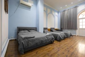 three beds in a room with blue walls and wooden floors at New Friends Mini-Hotel in Tashkent