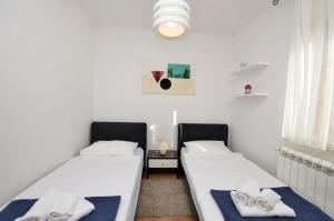 2 Betten in einem Zimmer mit weißen Wänden in der Unterkunft Apartment Maria in Labin