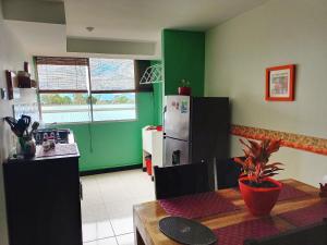 a kitchen with green walls and a table and a refrigerator at ApartHotel Nathalie B207 a 7min Parque del Café in Montenegro