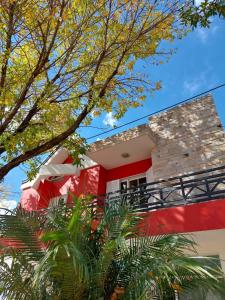 una casa roja y blanca con árboles en el primer plano en AltoRojo en Villa Elisa