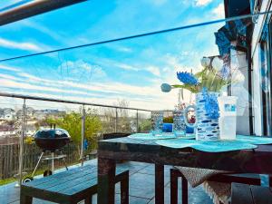 a table with vases and flowers on a balcony at Orchard Lodge -Coastal Retreat, new build, village views, private garden and terrace in Saint Brides Major