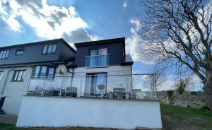 a house with a white wall in front of it at Orchard Lodge -Coastal Retreat, new build, village views, private garden and terrace in Saint Brides Major