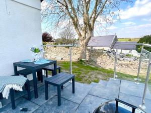 a patio with a table and benches and a tree at Orchard Lodge -Coastal Retreat, new build, village views, private garden and terrace in Saint Brides Major