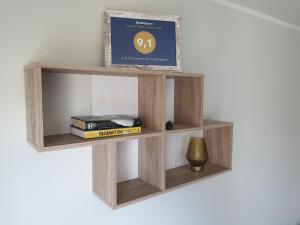 a wooden shelf with books and a vase on a wall at A.H Tammsaare Pärnu Apartment in Pärnu