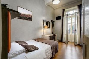 um quarto com uma cama, uma secretária e uma janela em The One Firenze em Florença