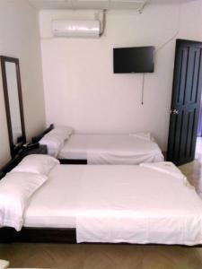 3 camas en una habitación con TV de pantalla plana en HOTEL DORADO PUERTO BERRIO, en Puerto Berrío