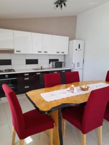 a kitchen with a wooden table and red chairs at loren in Pirovac +10 photos