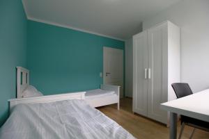 ein Schlafzimmer mit einer blauen Wand und einem Bett in der Unterkunft Messezimmer Hannover / Private rooms for exhibitions in Hannover