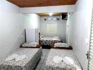 a room with two beds and a refrigerator at Hospedagem do Mineiro in Bonito