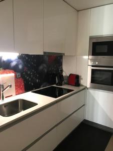 a white kitchen with a sink and a microwave at Casa da Nau in Vila do Conde
