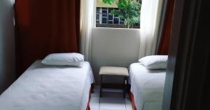 Cette petite chambre comprend 2 lits et une fenêtre. dans l'établissement UDIHOSTEL HOSPEDAGEN, à Uberlândia