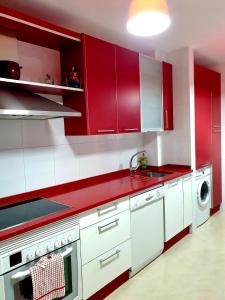 eine rote Küche mit weißen Schränken und einem Waschbecken in der Unterkunft Apartamento Miramar in Pontevedra