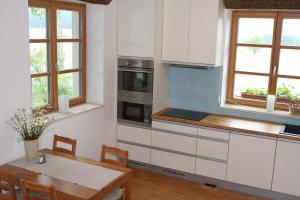 a kitchen with white cabinets and a wooden table at Horský apartmán Zvonička in Rejvíz
