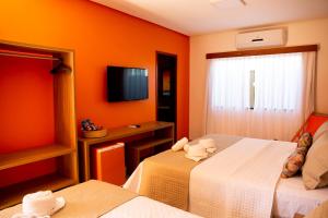 Habitación de hotel con 2 camas y TV en Pousada das Flores en Coqueiro