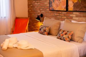 1 dormitorio con 1 cama con sábanas y almohadas blancas en Pousada das Flores en Coqueiro