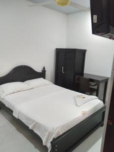 Schlafzimmer mit einem Bett mit einem schwarzen Kopfteil und einem Tisch in der Unterkunft HOTEL DORADO PUERTO BERRIO in Puerto Berrío