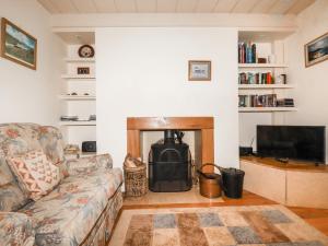 a living room with a couch and a fireplace at The Ark Cottage in Par