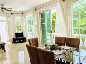 Un comedor con mesa y sillas y ventanas. en 9br 6ba Large groups! Best location in town Walk to beach, 5th ave Cozumel ferry, shopping, nightlife! Roof plunge pool!! Castillo Playacar Fase 1 25max, en Playa del Carmen