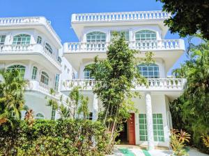 un gran edificio blanco con ventanas y árboles en 9br 6ba Large groups! Best location in town Walk to beach, 5th ave Cozumel ferry, shopping, nightlife! Roof plunge pool!! Castillo Playacar Fase 1 25max, en Playa del Carmen