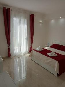 sypialnia z łóżkiem i oknem z czerwonymi zasłonami w obiekcie B&B Villa Bello w mieście Otranto