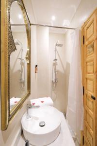 y baño con lavabo blanco y espejo. en Riad El Habib, en Marrakech