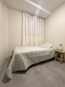 a white bedroom with a bed and a window at Departamento en Edificio Presidente Plaza España in Mendoza