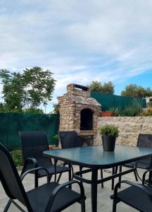 a patio with a table and chairs and a stone fireplace at Studio Apartment PineTree - Mali Lošinj in Mali Lošinj +7 photos
