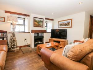 a living room with a couch and a television at Raceside Cottage in Silecroft