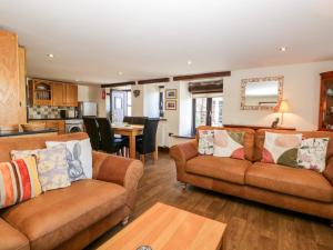 a living room with two couches and a kitchen at Raceside Cottage in Silecroft