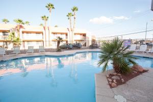 a large blue swimming pool with chairs and palm trees at Aviation Inn in Las Vegas