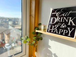 a sign that says eat drink and happy next to a window at Entire Stylish 1 Bedroom Flat with Free Parking in Dundee