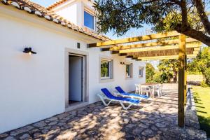 un patio con sillas azules y una mesa frente a una casa en Quinta do Arneiro, en Azeitão