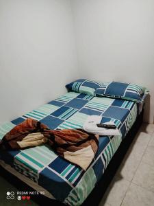 ein Bett mit einer Decke und Kissen darauf in der Unterkunft BARU ESTELAR in Medellín