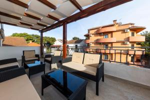 a balcony with chairs and tables and a building at Apartman Lana in Biograd na Moru
