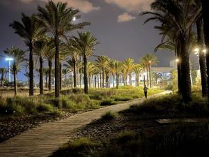 a person walking down a path with palm trees at Appartement ‘’Los Pinos’’ 50m de la plage in Grao de Castellón