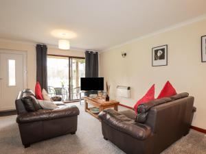a living room with two leather chairs and a television at Stone Water Cottage in Contin