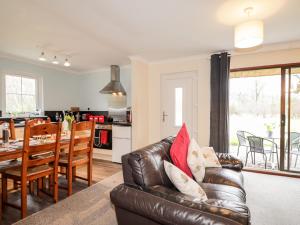 a living room with a leather couch and a dining room at Stone Water Cottage in Contin
