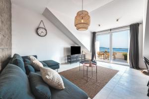 a living room with a blue couch and a clock at Divine Apartment in Mlini