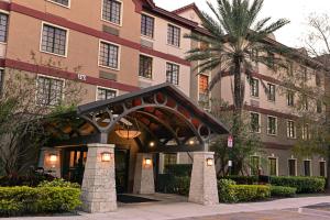 a hotel with a building with a palm tree in front of it at Sonesta ES Suites Fort Lauderdale Plantation in Plantation
