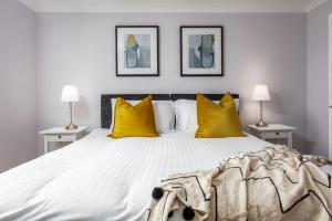 a bedroom with a large bed with yellow pillows at Shore View - Donnini Apartments in Prestwick