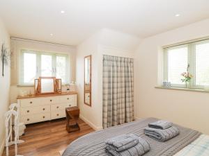 a bedroom with a bed and a dresser and windows at Shephards Retreat in Kingsdon