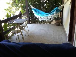 eine Terrasse mit einer Hängematte sowie einem Tisch und Stühlen in der Unterkunft Recanto Suítes in Araruama