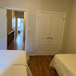 - une chambre blanche avec 2 lits et un couloir dans l'établissement Harlem House, à New York